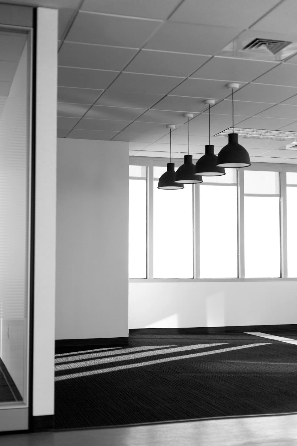 Luminoso ufficio moderno con grandi finestre e lampade a sospensione.